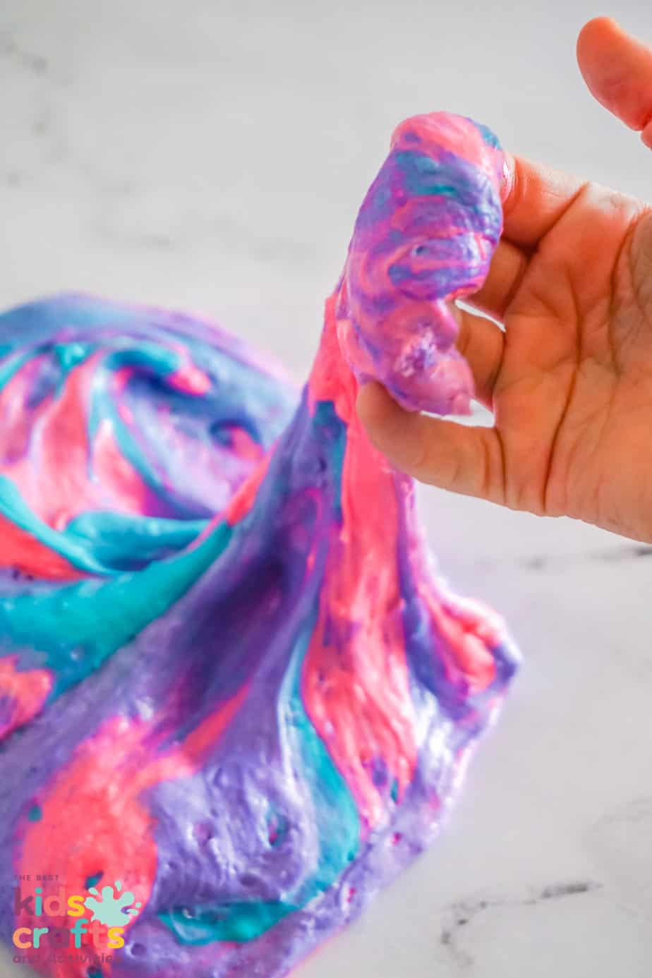 kids hand playing and stretching Fluffy Unicorn Slime Recipe
