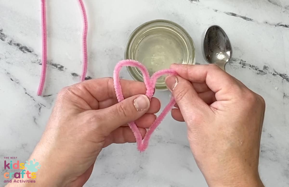 pipe cleaner being shaped into a heart shape