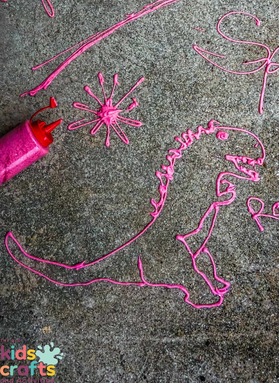A pink chalk drawing of a dinosaur on a concrete floor.